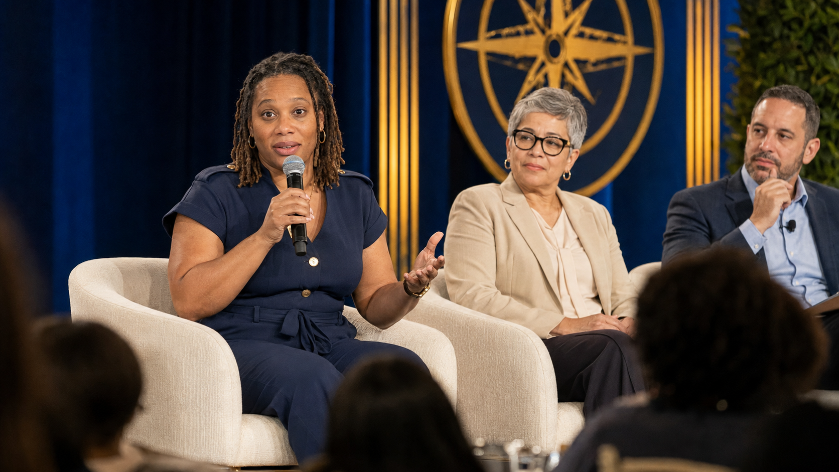 Nichole Braxton speaks into a microphone during a fireside panel discussion with two other education leaders.